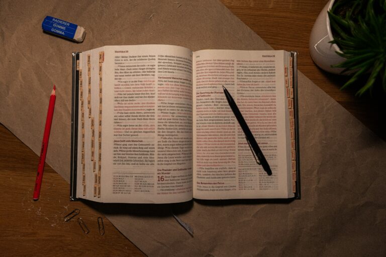An open book on a table with a pen and pencil