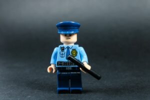 Lego police officer holding a baton against dark background