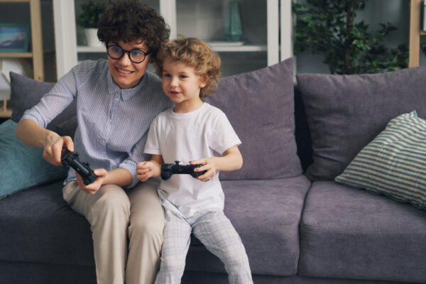 a woman and a child sitting on a couch playing a video game
