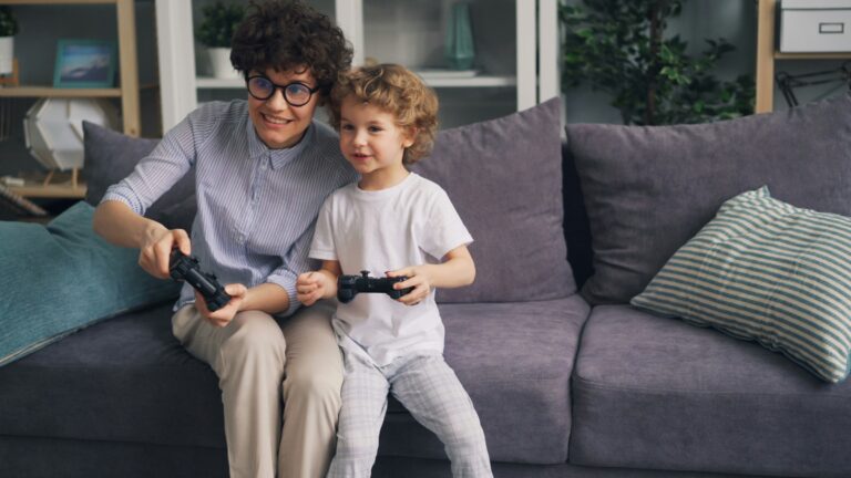 a woman and a child sitting on a couch playing a video game