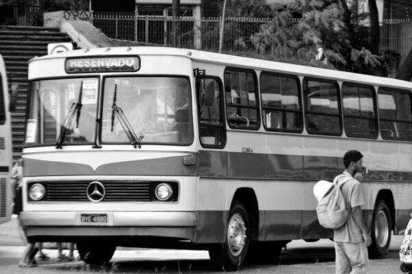 a black and white photo of a bus and people