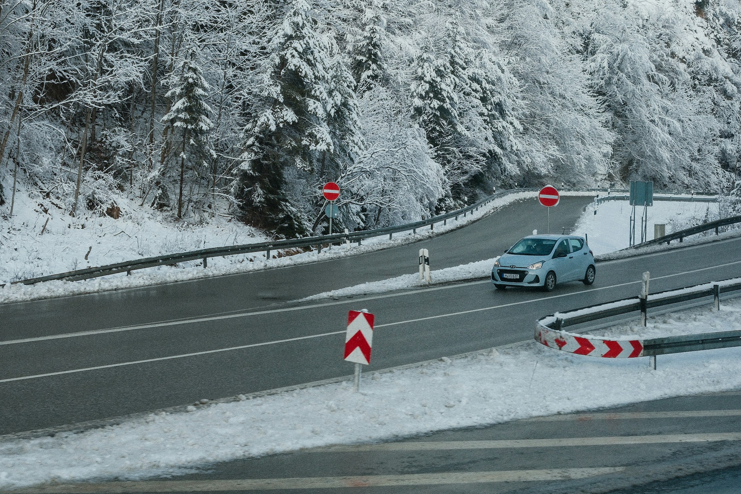 A car is driving down a snowy road