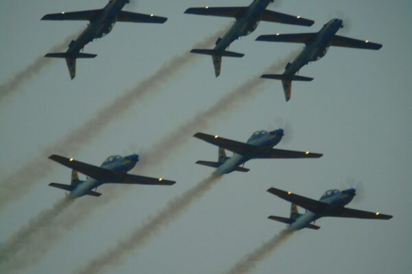 Six airplanes fly in formation, leaving smoke trails.