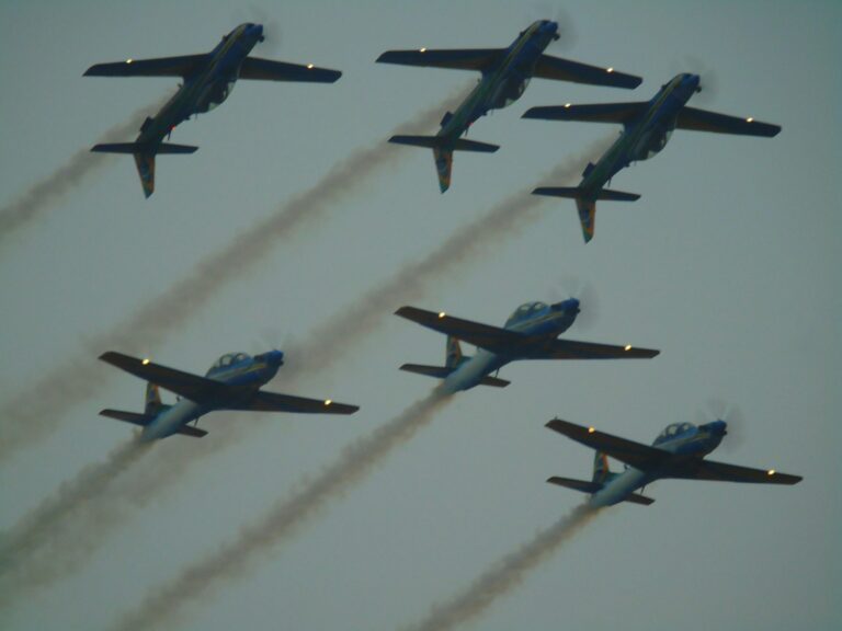 Six airplanes fly in formation, leaving smoke trails.