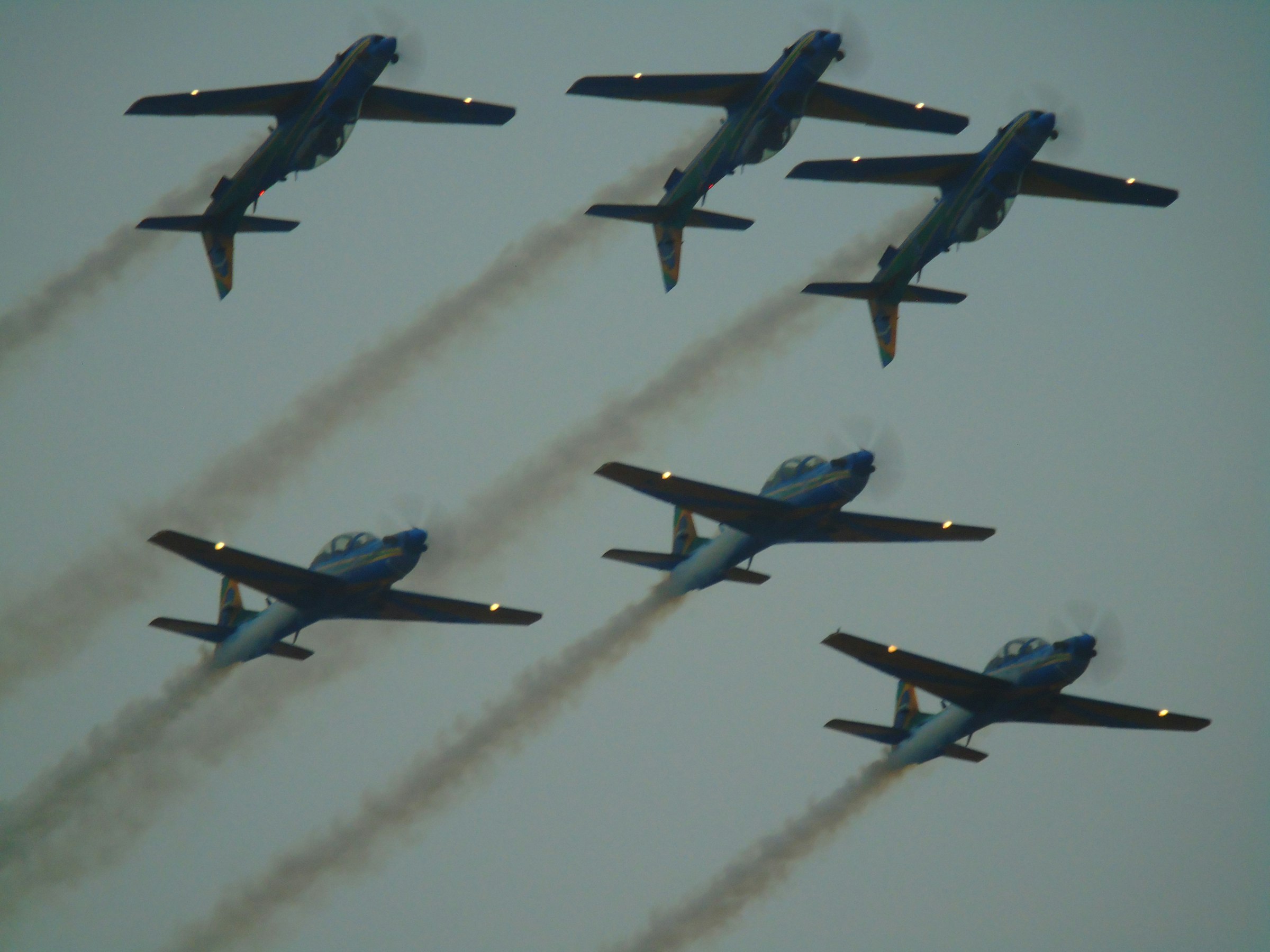 Six airplanes fly in formation, leaving smoke trails.