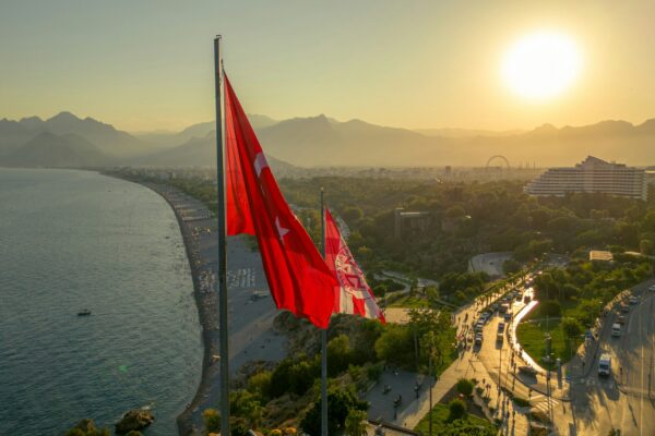 Turkish flag flies over a coastal city at sunset.