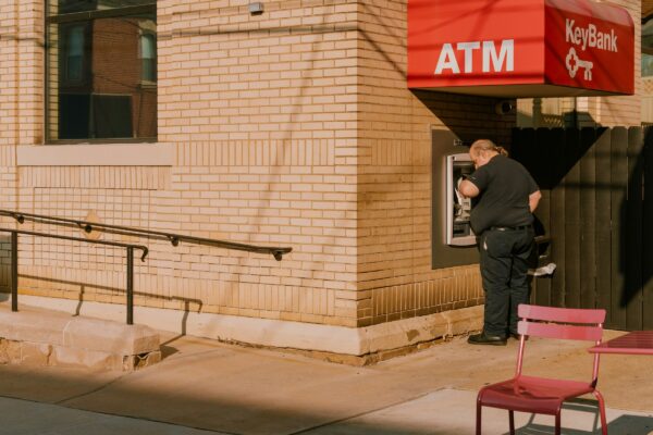 A man standing outside of a building next to a red chair