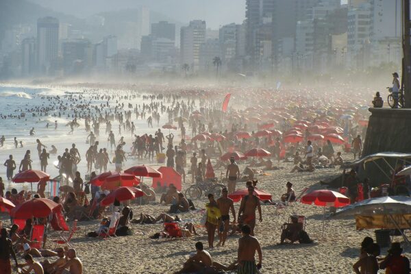 a crowded beach with many people and umbrellas