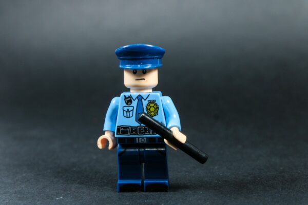 Lego police officer holding a baton against dark background