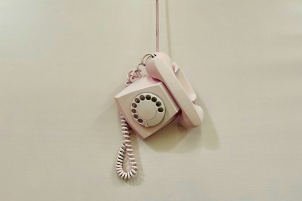 a pink phone hanging from a cord on a wall