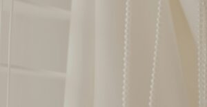a close up of a white curtain with beads hanging from it