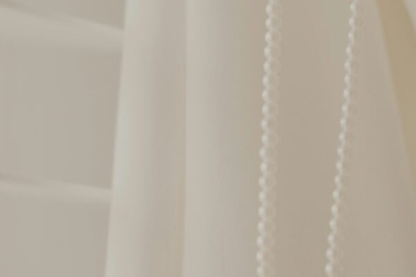 a close up of a white curtain with beads hanging from it
