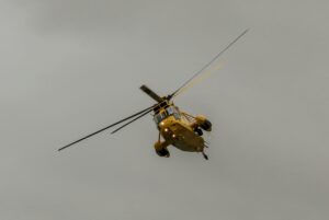 a yellow helicopter flying through a cloudy sky