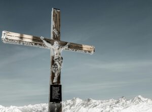 brown wooden cross on snow covered mountain under blue sky during daytime