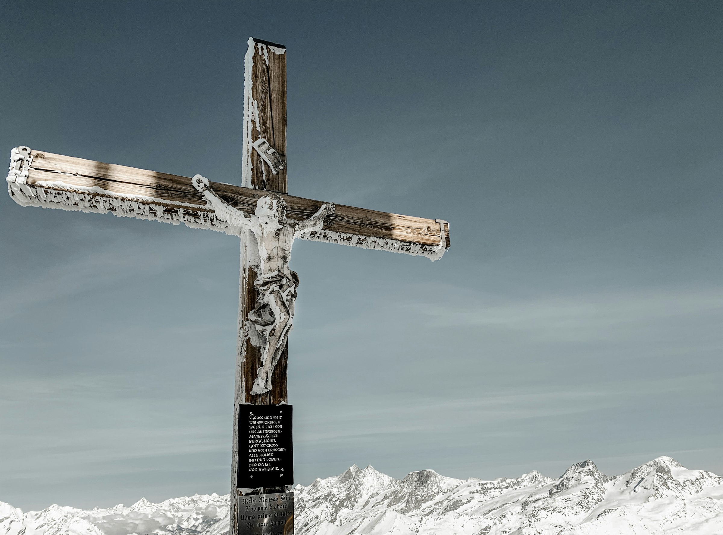 brown wooden cross on snow covered mountain under blue sky during daytime