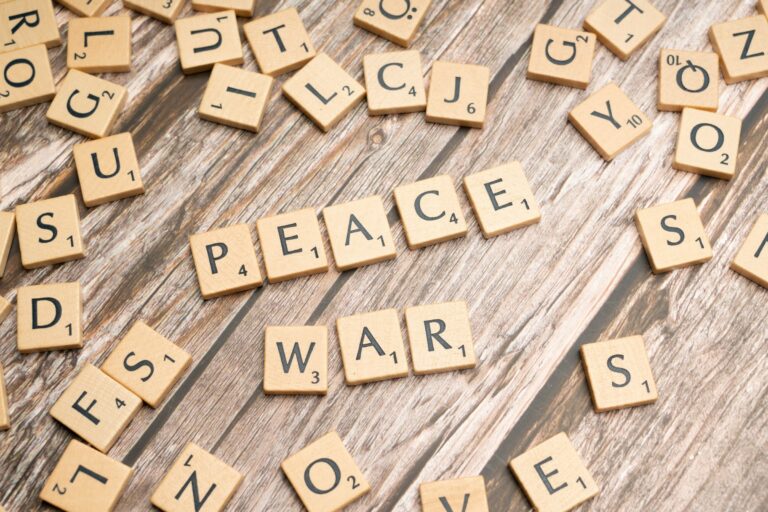 scrabble letters spelling peace and war on a wooden surface