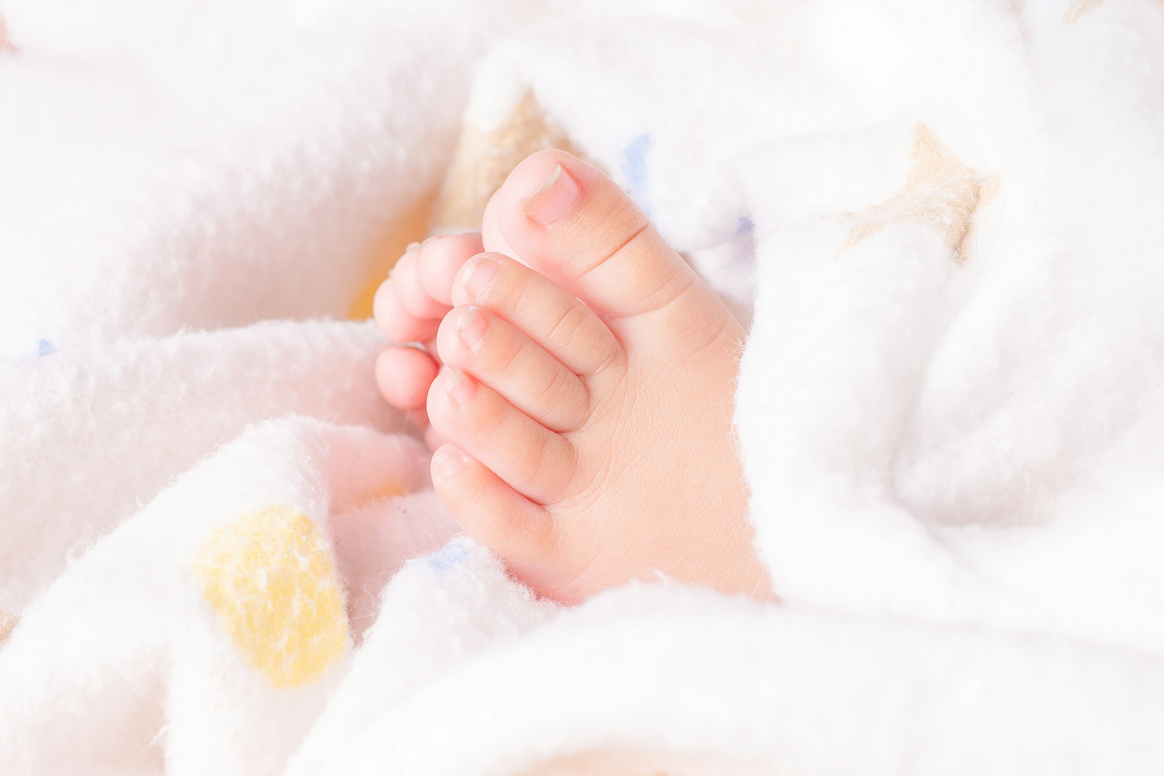 Close-up of tiny baby feet wrapped in soft blanket
