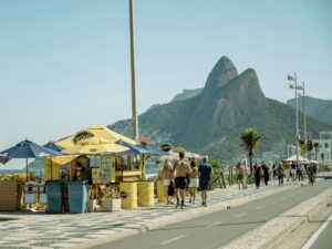 A group of people walking down a street next to a beach
