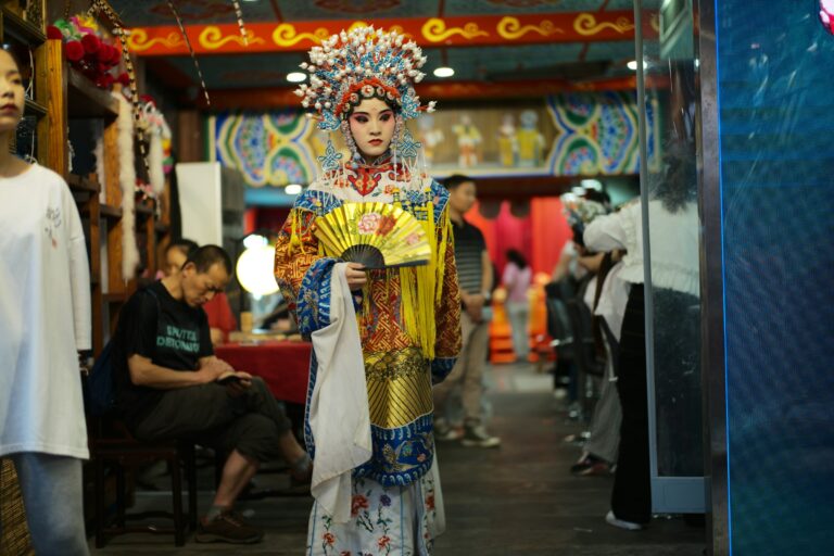 Performer in ornate costume holds a fan