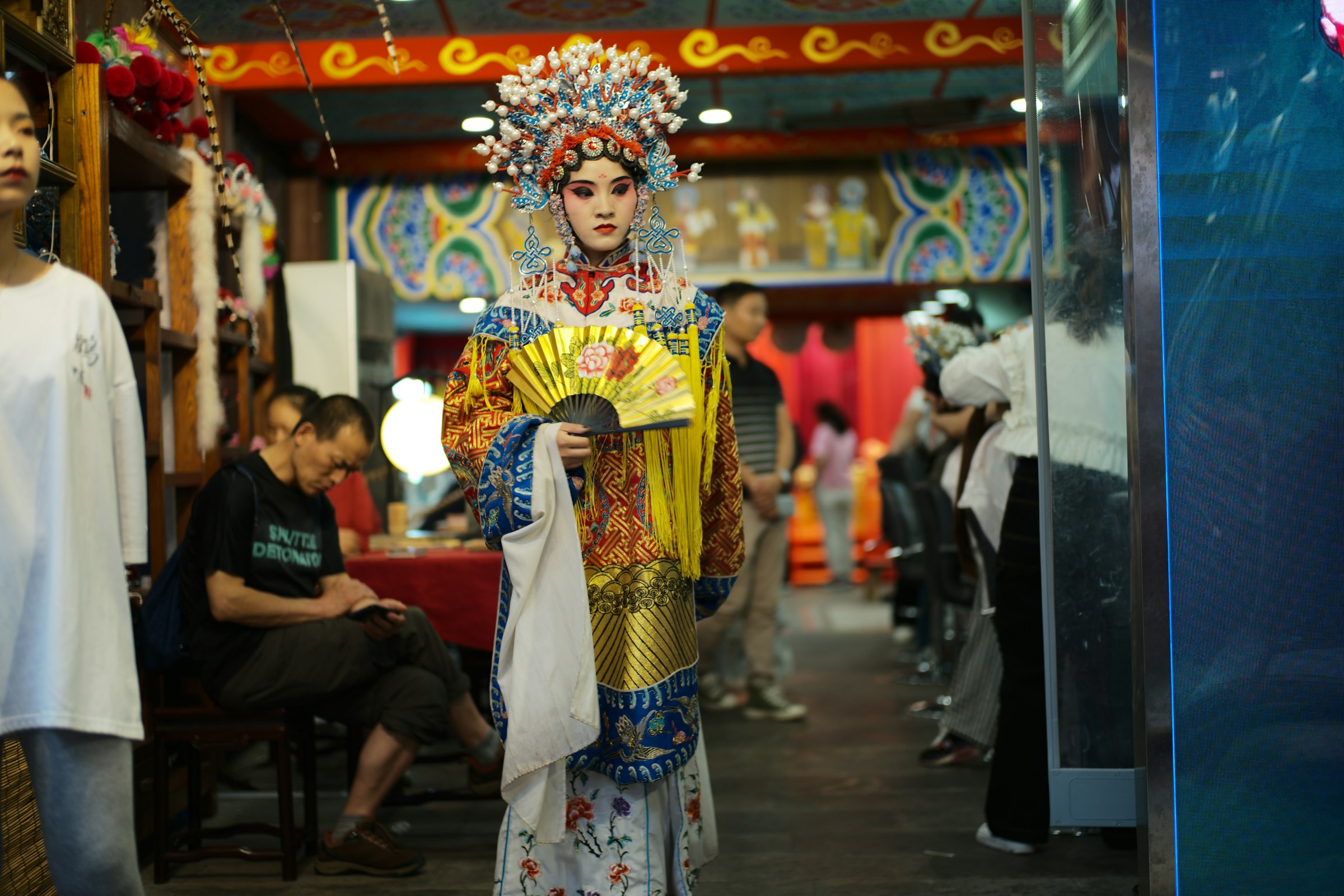 Performer in ornate costume holds a fan
