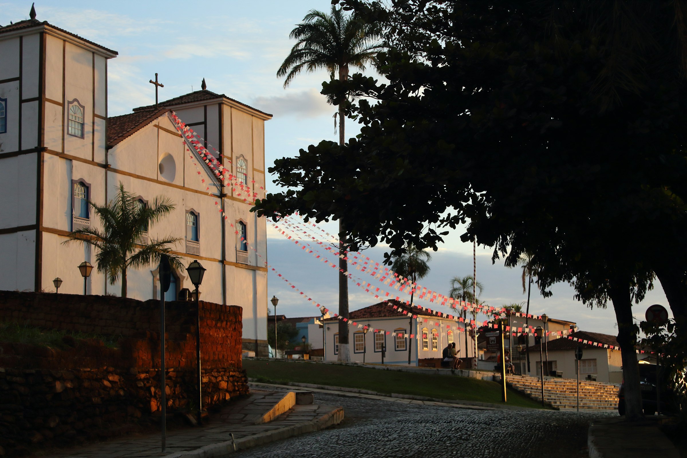 Church building with palm trees and decorations at sunset.