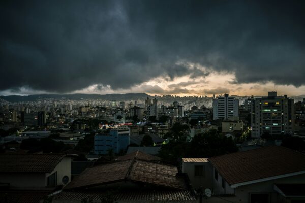 city with high rise buildings under gray clouds during night time