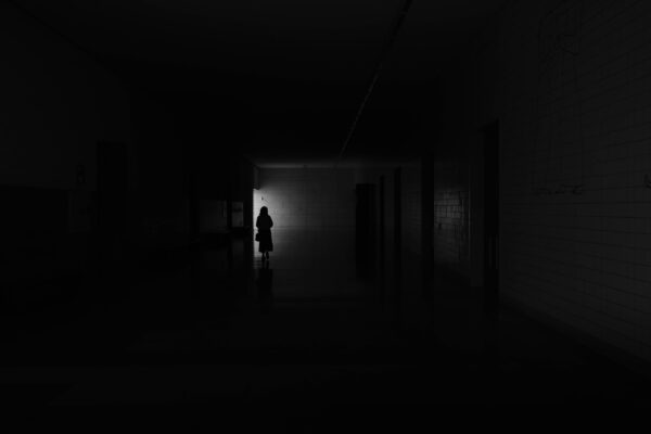 A person standing in a dark hallway at night