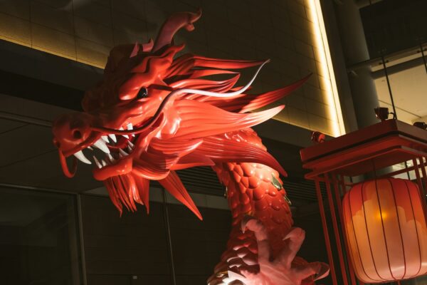 a large red dragon statue next to a lantern