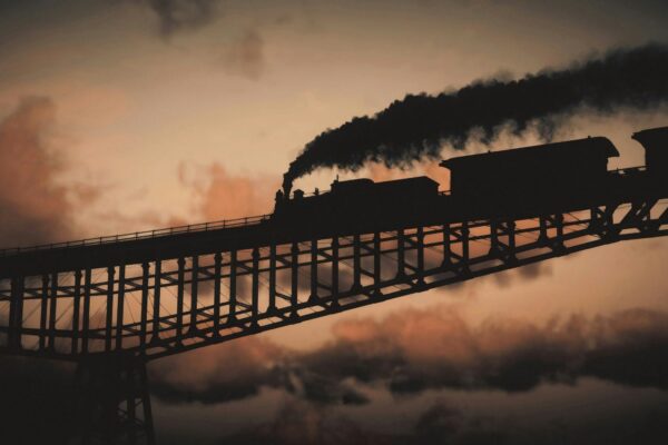 a train traveling over a bridge with smoke pouring out of it