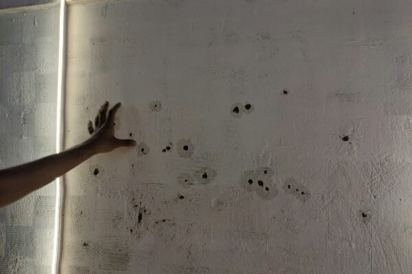 a person reaching for bullet holes in a wall