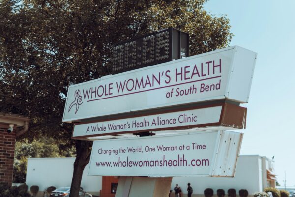 a sign with a tree in the background