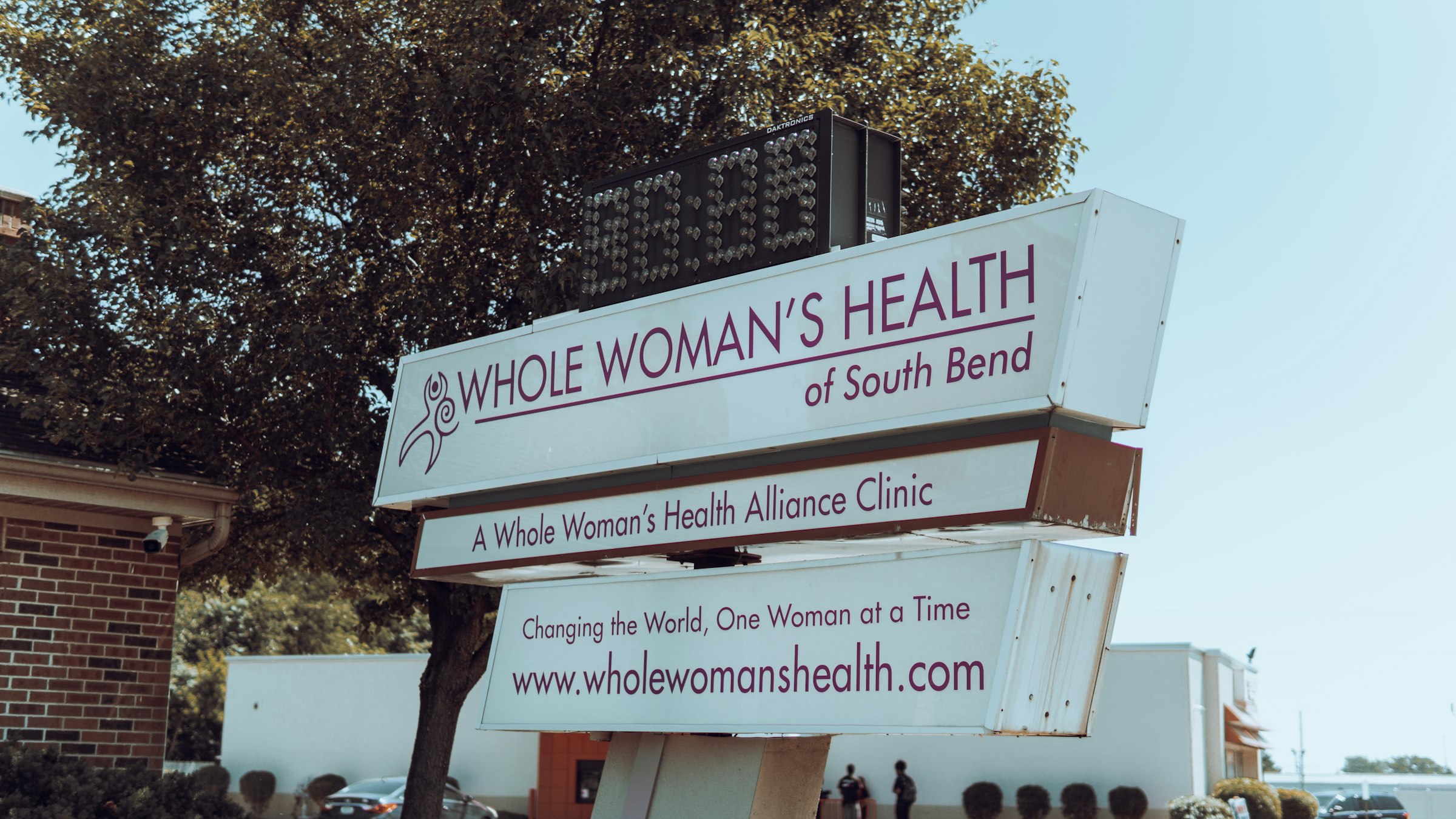 a sign with a tree in the background