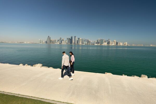 two people standing on a ledge overlooking a body of water