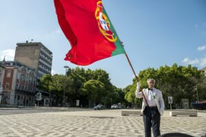 Man holding a large portuguese flag outdoors