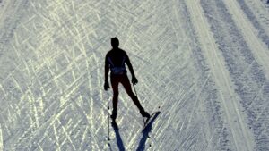 Silhouette of cross-country skier on snowy track.