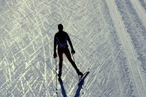 Silhouette of cross-country skier on snowy track.