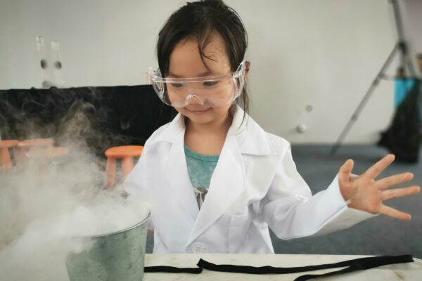 a little girl wearing a white lab coat and goggles