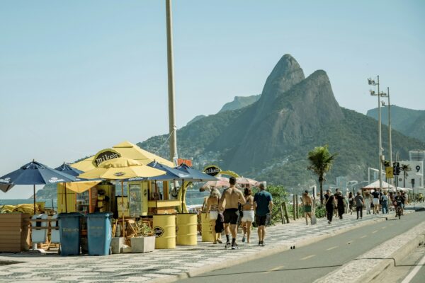 A group of people walking down a street next to a beach