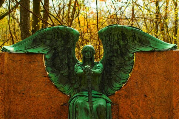 a statue of an angel sitting on top of a stone wall