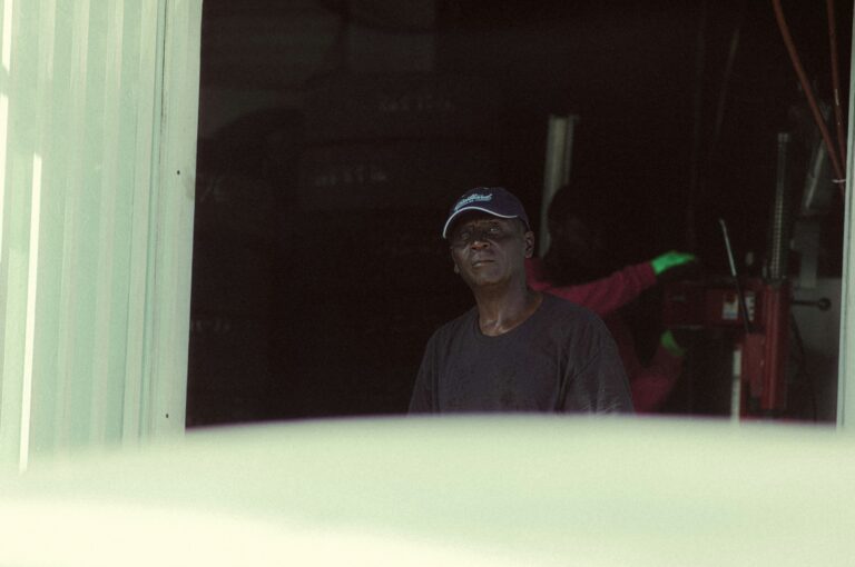 A man stands in the doorway of a dark garage.