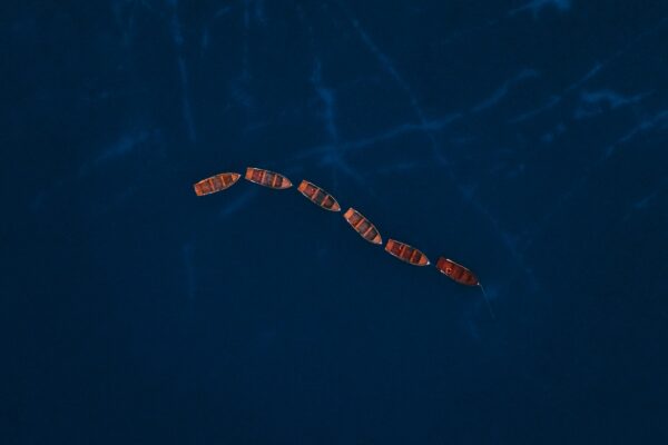 Several boats sailing in formation on the ocean.