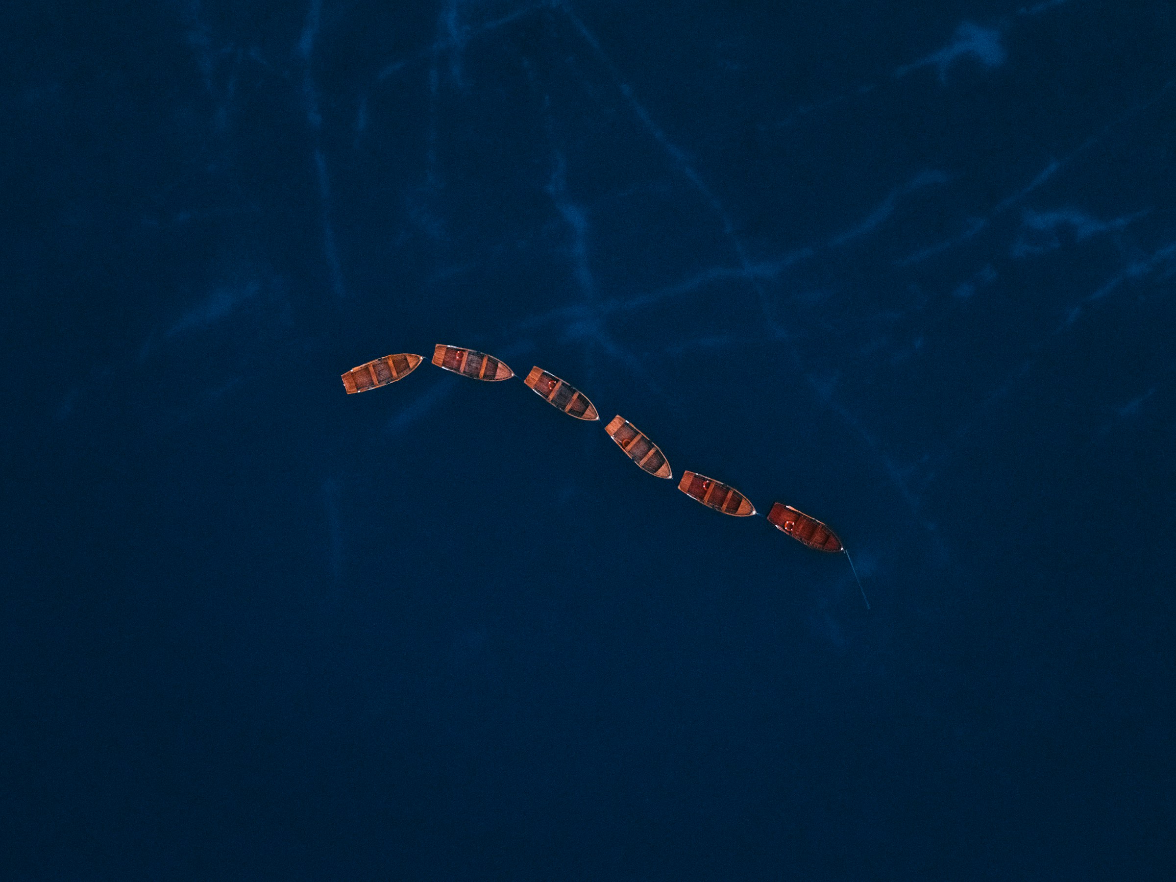 Several boats sailing in formation on the ocean.
