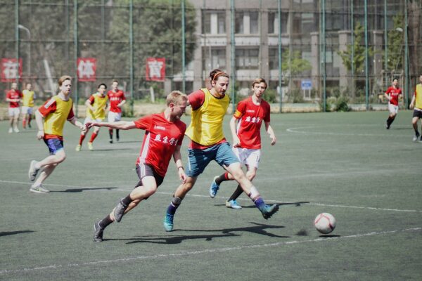 men playing soccer on field with fence