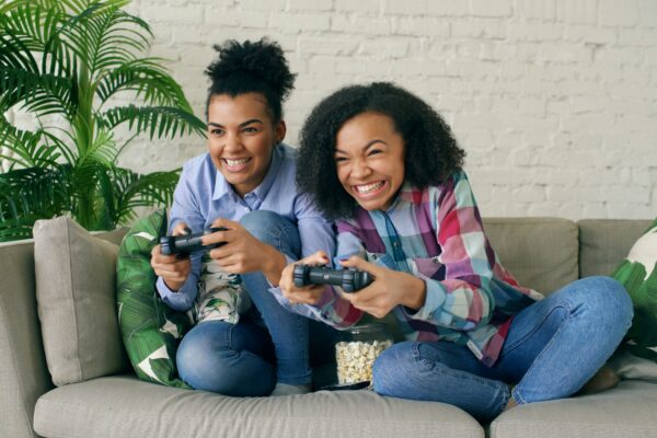 Two smiling women playing video games on couch