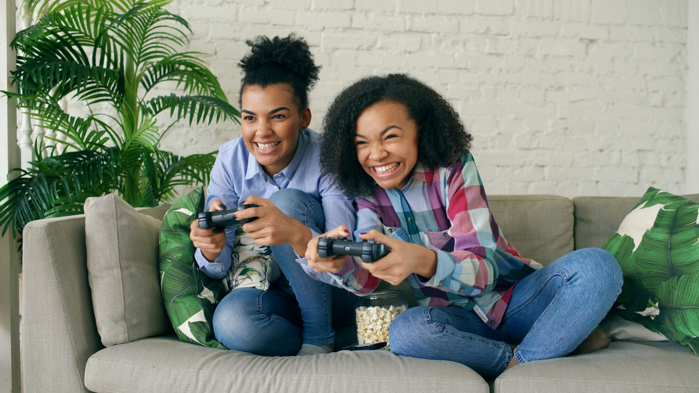 Two smiling women playing video games on couch
