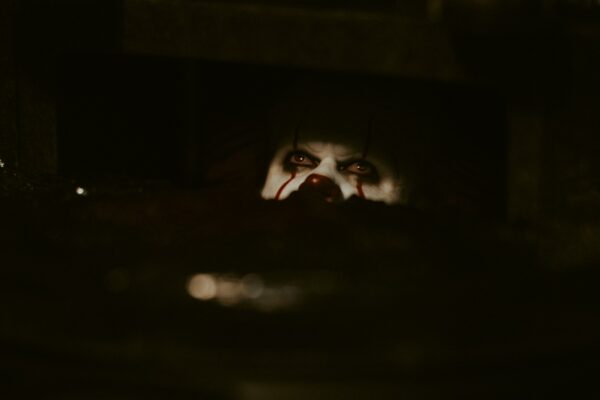 A creepy clown peeking from darkness