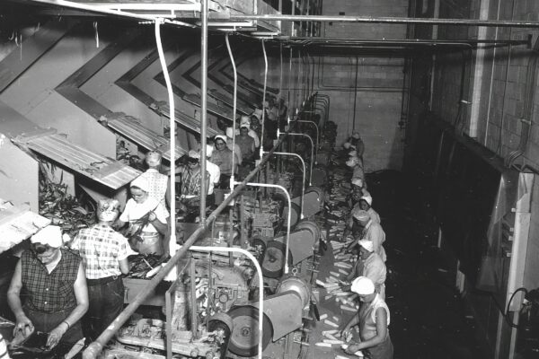 a black and white photo of men working in a factory